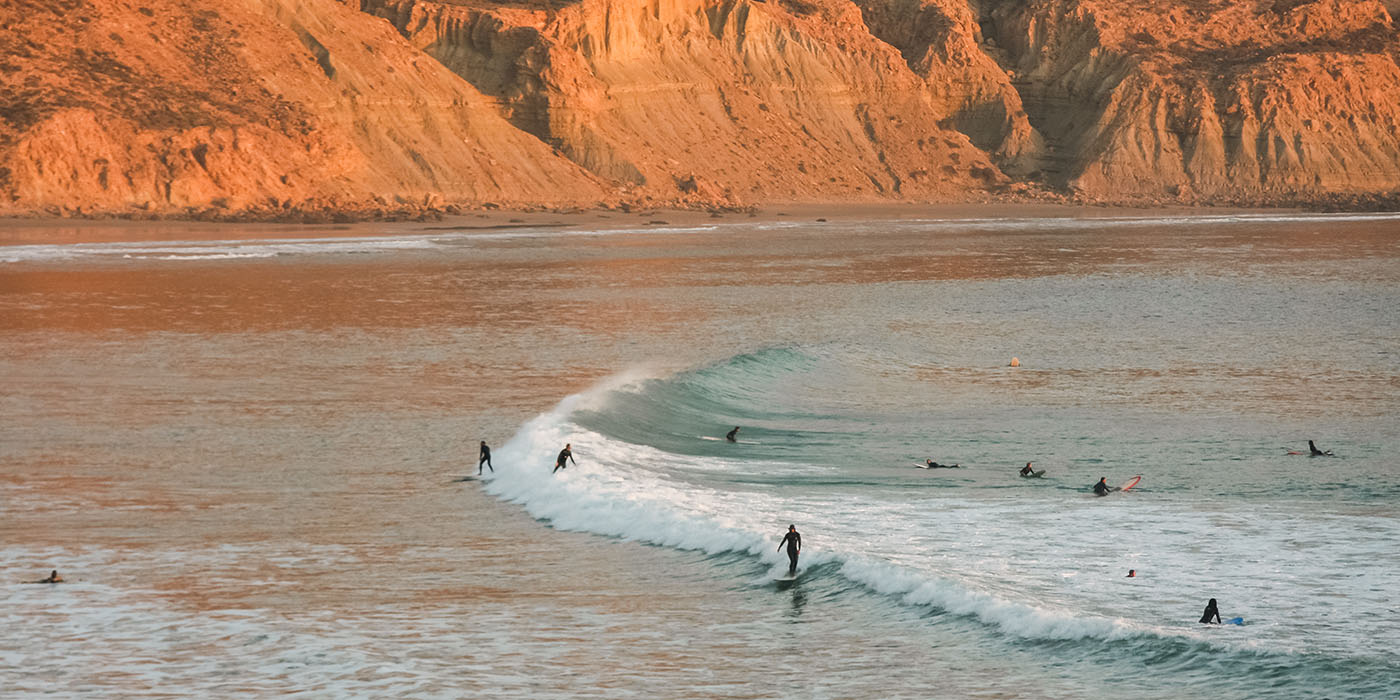 Waves breaking and surfers surfing in Imsouane, Morocco