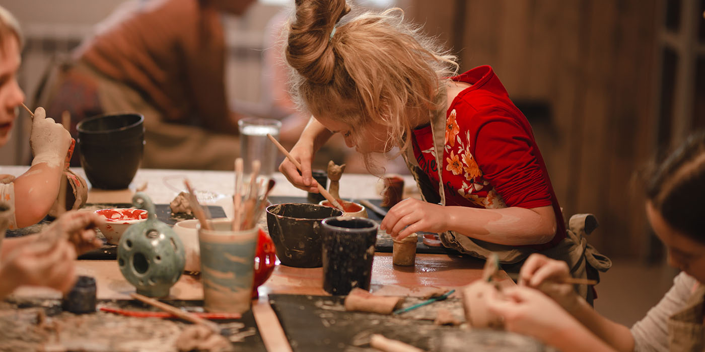 Young seven years old girl in pottery workshop creating a bowl from clay. Pottery workshop for kids